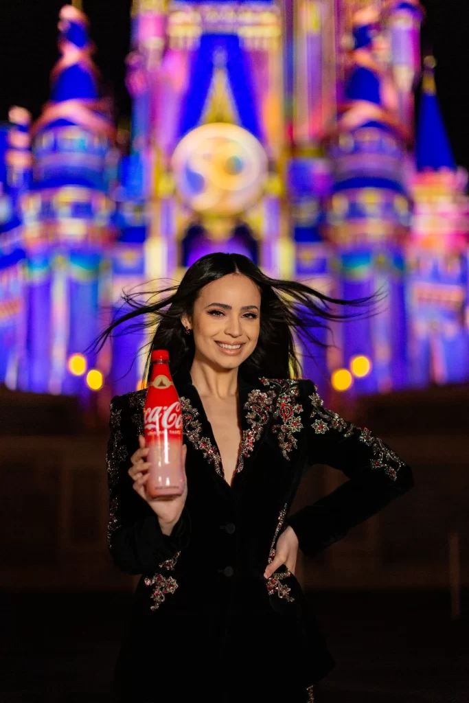 To celebrate the 50-year collaboration between Walt Disney World Resort and Coca-Cola, Sofia Carson helped unveil five unique co-branded collectible bottles that are now available exclusively at the resort during the 50th Anniversary Celebration. Sold at locations throughout each of the four Walt Disney World theme parks, there are four different bottles featuring each of the 4 park icons with their own unique EARisdescent color on the labels, plus a fifth bottle with a special gold label. The bottles are shaped just like the bottles that were sold at Walt Disney World when it opened in 1971