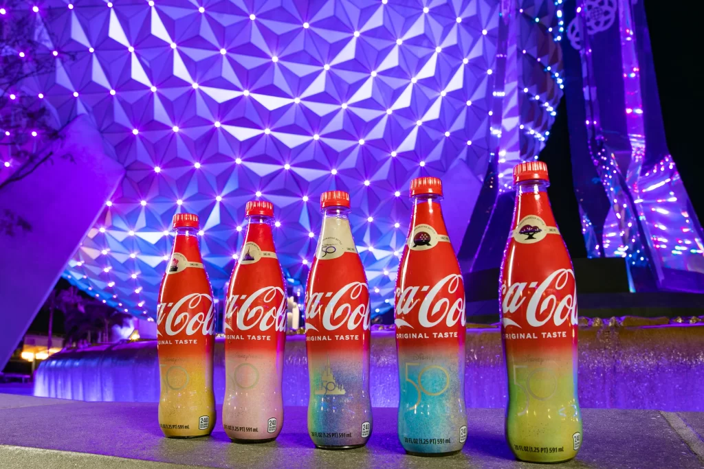 To celebrate the 50-year collaboration between Walt Disney World Resort and Coca-Cola, Sofia Carson helped unveil five unique co-branded collectible bottles that are now available exclusively at the resort during the 50th Anniversary Celebration. Sold at locations throughout each of the four Walt Disney World theme parks, there are four different bottles featuring each of the 4 park icons with their own unique EARisdescent color on the labels, plus a fifth bottle with a special gold label. The bottles are shaped just like the bottles that were sold at Walt Disney World when it opened in 1971