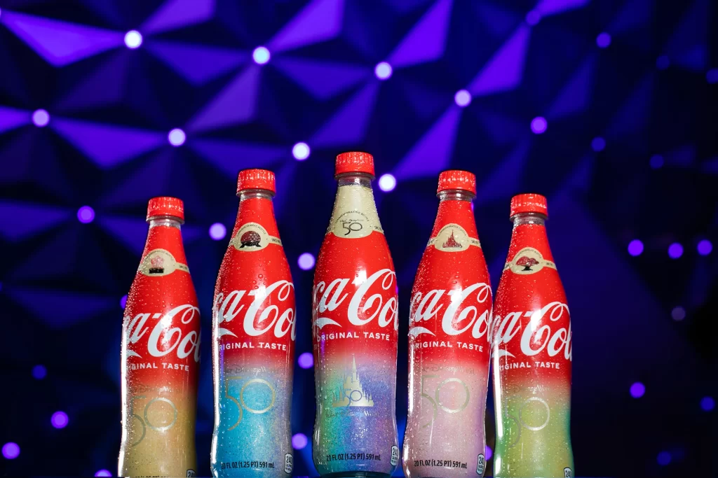 To celebrate the 50-year collaboration between Walt Disney World Resort and Coca-Cola, Sofia Carson helped unveil five unique co-branded collectible bottles that are now available exclusively at the resort during the 50th Anniversary Celebration. Sold at locations throughout each of the four Walt Disney World theme parks, there are four different bottles featuring each of the 4 park icons with their own unique EARisdescent color on the labels, plus a fifth bottle with a special gold label. The bottles are shaped just like the bottles that were sold at Walt Disney World when it opened in 1971