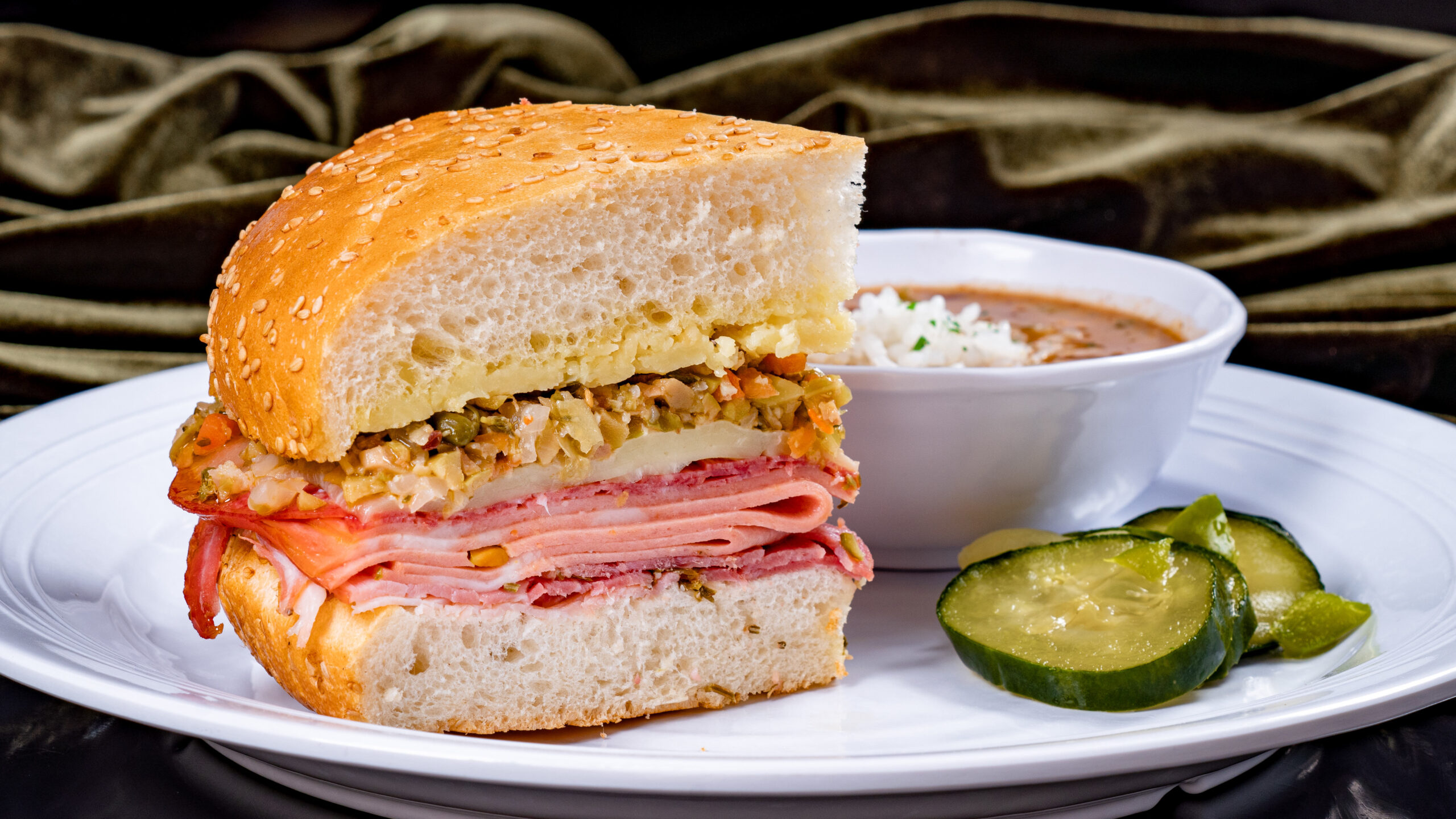 Muffuletta Sandwich (Tiana’s Palace at Disneyland Park in Anaheim, Calif.) – mortadella, salami, rosemary ham, cheddar, provolone and house-made olive relish on toasted New Orleans sesame seed bread, served with red beans & rice and house-made pickles. Available beginning Sept. 7, 2023. For more details, visit DisneyParksBlog.com. (David Nguyen/Disneyland Resort)