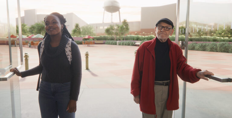 In a scene from the short film Once Upon a Studio, an intern and Disney Legend Burny Mattinson stand just outside of the doors of the Roy E. Disney Animation Building in Burbank, California. The Walt Disney Studios Water Tower is just visible in the background.