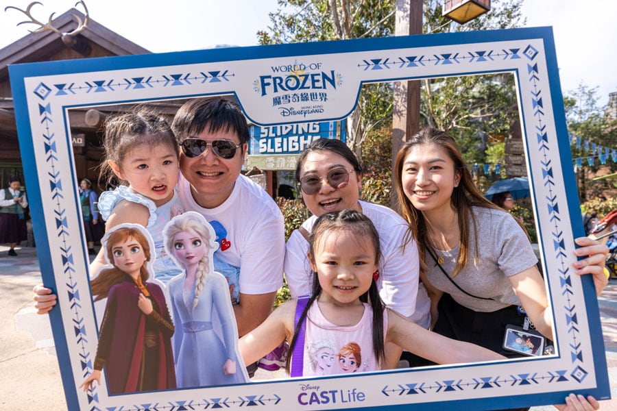 A family poses together holding a World of Frozen photo prop