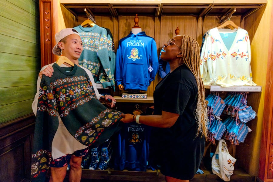 Two cast members look at themed World of Frozen shirts, sweaters and souvenir bags