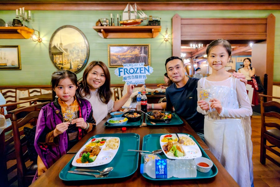 A family including two daughters wearing Anna and Elsa costumes enjoying a meal