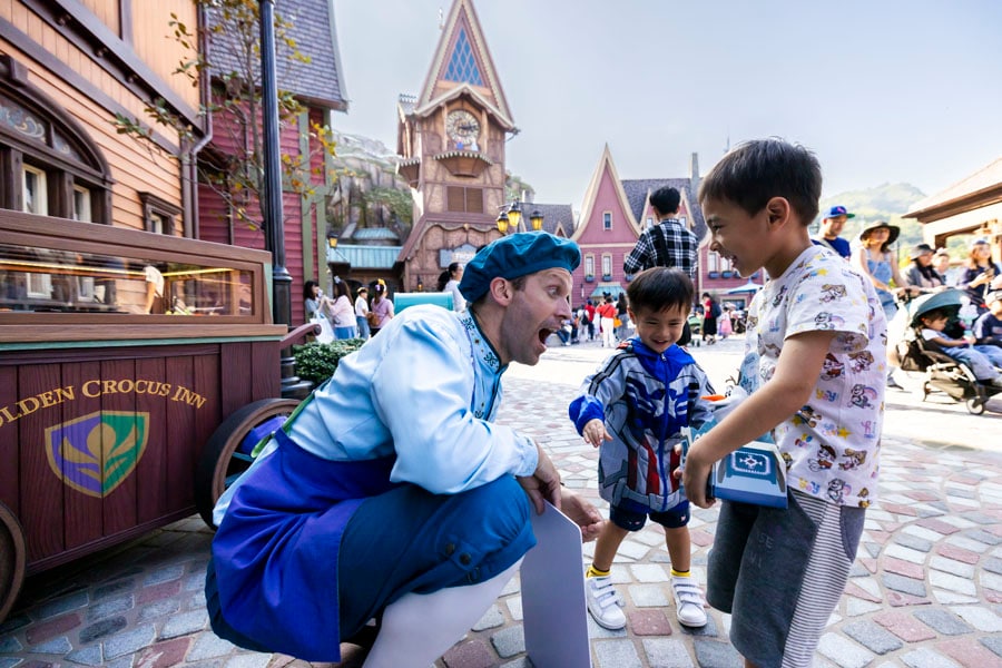 A citizen of Arendelle interacting with a young guest carrying an Olaf toy