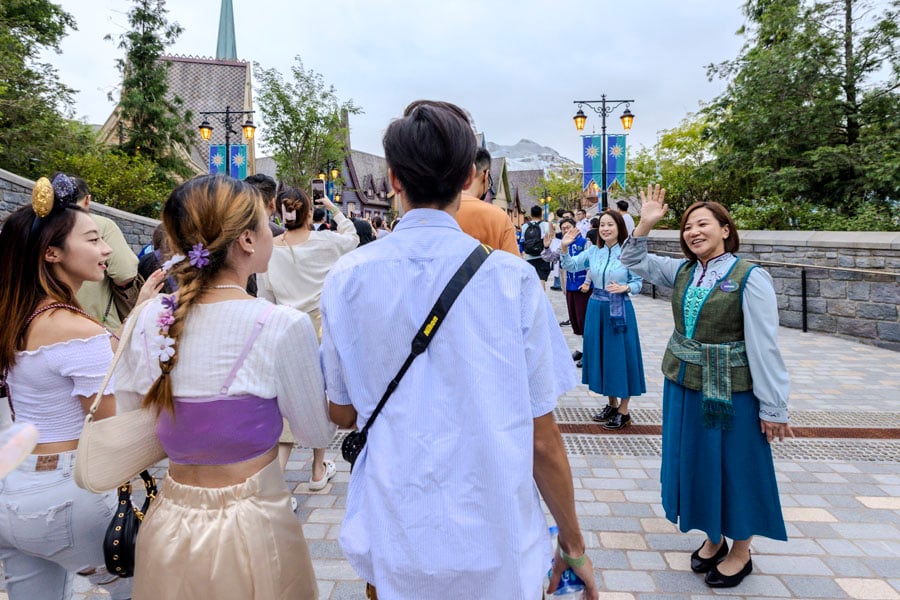 Cast members waving to guests as they enter World of Frozen