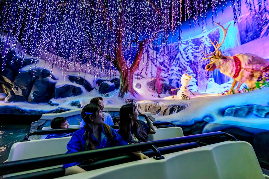 A family riding Frozen Ever After, looking at Olaf and Sven from their boat