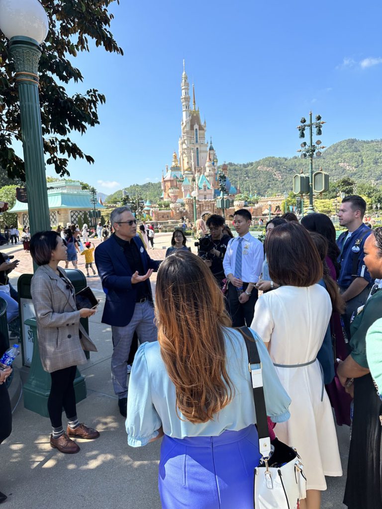 The Disney Ambassadors listen to an Imagineer as they explain the redesign of the Castle of Magical Dreams in front of them