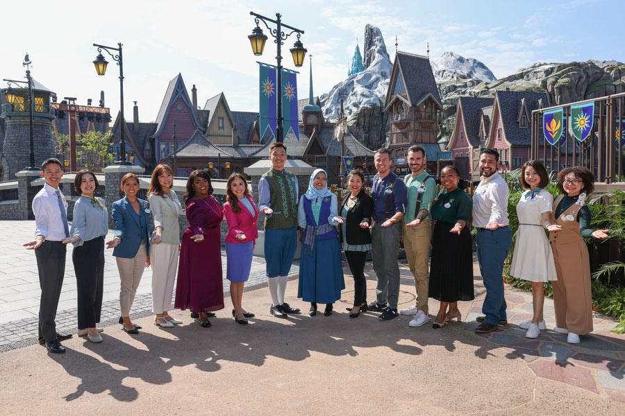 The Disney Ambassadors smiling and posing with two citizens of Arendelle following a tour of World of Frozen, behind them