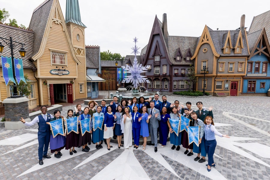 The Disney Ambassadors gather with citizens of Arendelle in World of Frozen, displaying the signed friendship flags they exchanged