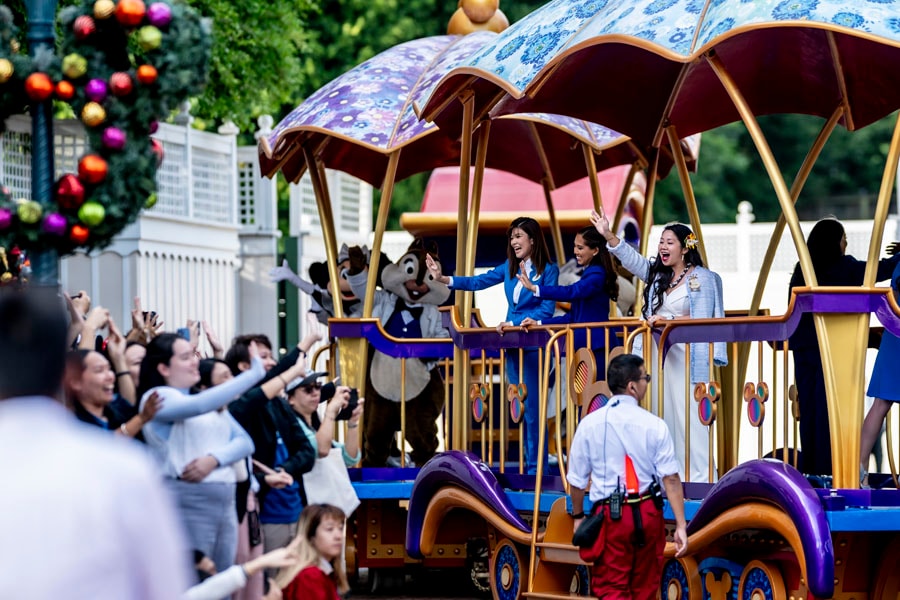 Disney Ambassadors wave at guests while riding aboard a parade float down Main Street, U.S.A. at Hong Kong Disneyland