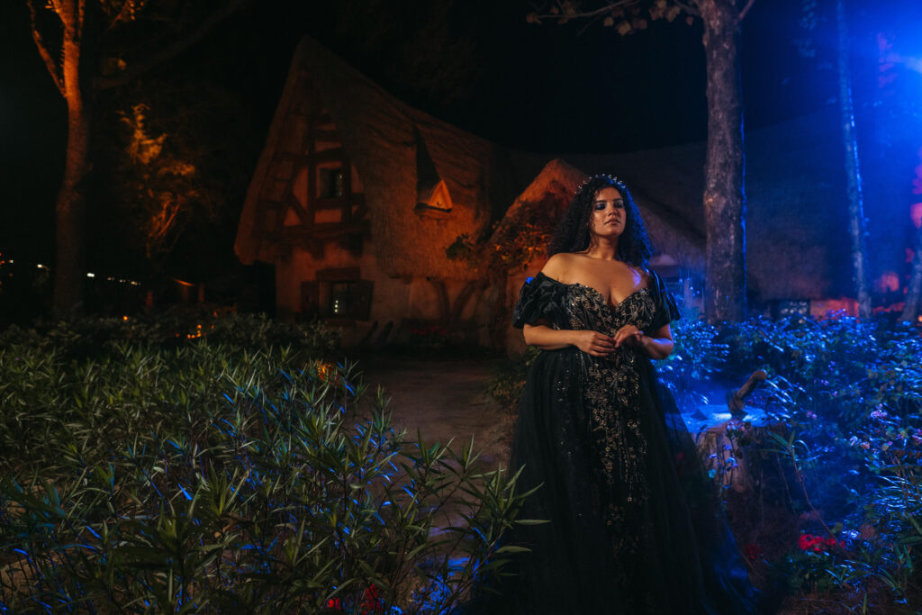The new Disney’s evil Queen wedding gown is shown near Seven Dwarves Mine Train attraction in Magic Kingdom Park at Walt Disney World Resort in Lake Buena Vista, Fla. It is one of four new gowns inspired by Disney Villains and introduced as part of the 2024 Disney’s Fairy Tale Weddings collection from Allure Bridals. Inspired by the villain from Disney’s “Snow White and the Seven Dwarves,” the gown is adorned with linear lace, 3D floral embellishments, beads and sequins delicately scattered over tulle. The silhouette features a sweetheart neckline leading into a peaked bodice complemented by eye-catching embroidery. The gown is available in ivory, black or gold with a wrapped ruffle shawl for added elegance. (Claire Celeste, Photographer)