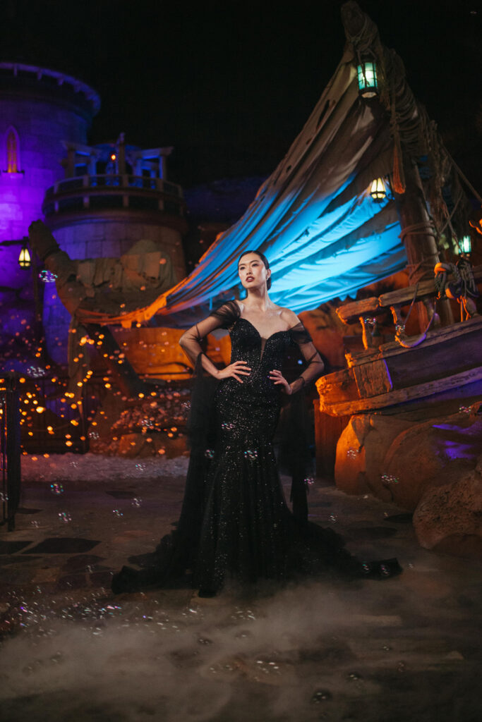 The new Disney’s Ursula wedding gown is shown in front of the Under the Sea – Journey of the Little Mermaid attraction in Magic Kingdom Park at Walt Disney World Resort in Lake Buena Vista, Fla. It is one of four new gowns inspired by Disney Villains and introduced as part of the 2024 Disney’s Fairy Tale Weddings collection from Allure Bridals. Inspired by the famous sea witch, the gown features a mermaid silhouette adorned with tonal sparkle beadwork on the bodice. It is available in ivory or black and features detachable sheer sleeves with ruffled detailing at the cuffs. (Claire Celeste, Photographer)