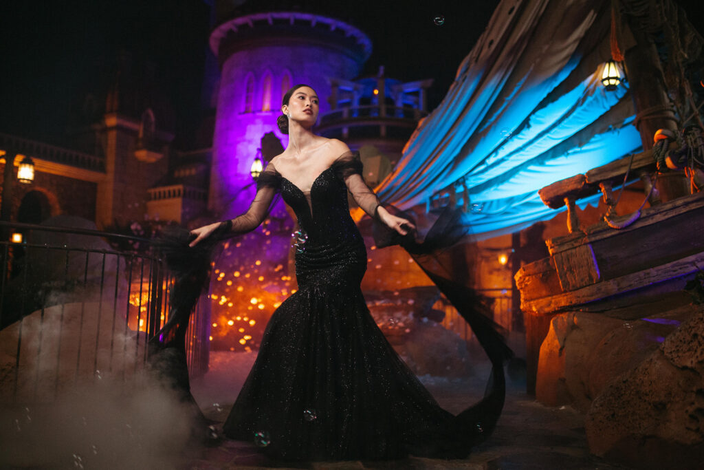 The new Disney’s Ursula wedding gown is shown in front of the Under the Sea – Journey of the Little Mermaid attraction in Magic Kingdom Park at Walt Disney World Resort in Lake Buena Vista, Fla. It is one of four new gowns inspired by Disney Villains and introduced as part of the 2024 Disney’s Fairy Tale Weddings collection from Allure Bridals. Inspired by the famous sea witch, the gown features a mermaid silhouette adorned with tonal sparkle beadwork on the bodice. It is available in ivory or black and features detachable sheer sleeves with ruffled detailing at the cuffs. (Claire Celeste, Photographer)