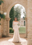 Elegantly stitched lacework trails across the Disney's Jasmine Platinum gown, which pairs an understated and altogether stunning off-shoulder bodice and full length sleeve with the slim lines of a sheath skirt.
