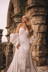 Unfurling, oversized lacy blooms, representative of the Princess's passionate curiosity and love of beauty, adorn the sheath silhouette of our Disney's Rapunzel Platinum gown. Swirls of satiny Mikado wrap the arms and define the train of this stunning gown.