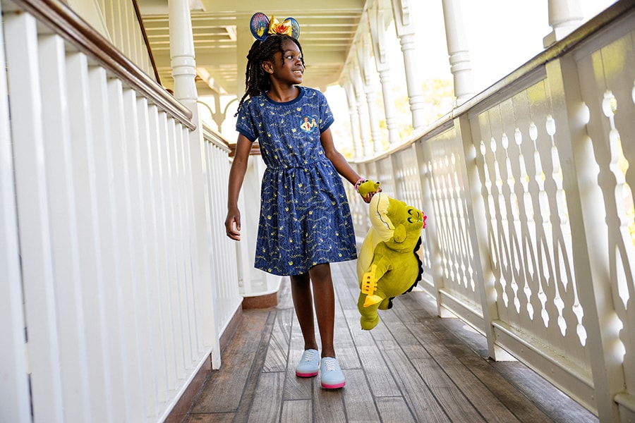 Girl wearing Tiana's Bayou Adventure apparel holding Louis plush