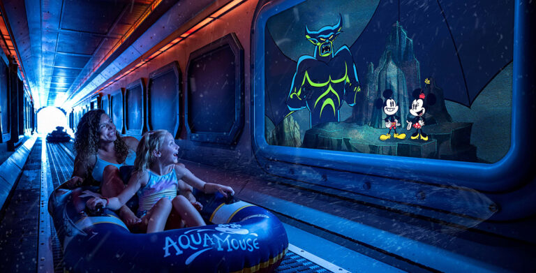 An adult and a child ride an inflatable tube on the AquaMouse. They are looking at an animated scene on a screen depicting Chernabog, Mickey Mouse, and Minnie Mouse