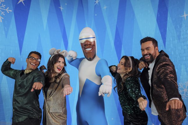 Guests pose with Frozone in front of a blue backdrop