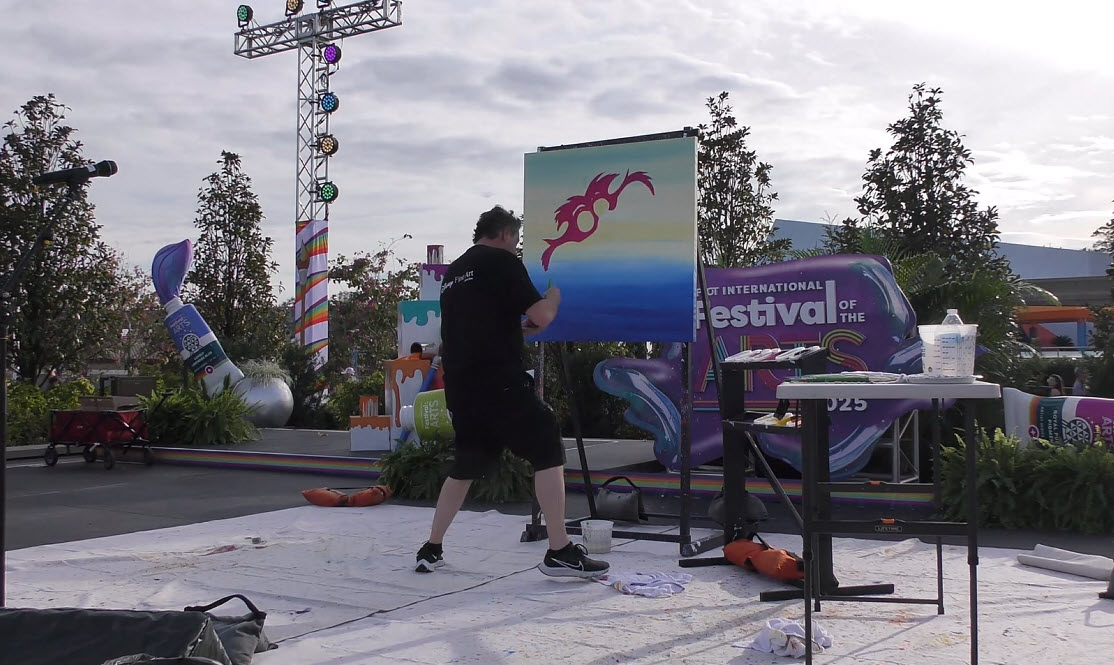 Trevor Carlton brings the whimsical Cheshire Cat to life during his live painting performance at the 2025 EPCOT Festival of the Arts in CommuniCore Plaza.