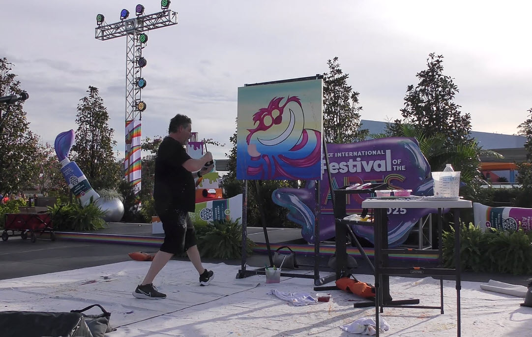 Trevor Carlton brings the whimsical Cheshire Cat to life during his live painting performance at the 2025 EPCOT Festival of the Arts in CommuniCore Plaza.