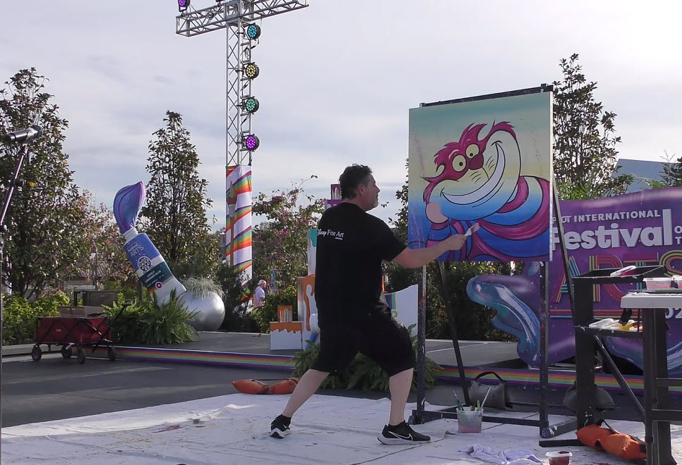 Trevor Carlton brings the whimsical Cheshire Cat to life during his live painting performance at the 2025 EPCOT Festival of the Arts in CommuniCore Plaza.
