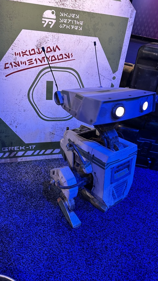 GREK-17, the thoughtful green BDX droid, pauses to observe its surroundings at Star Wars: Galaxy’s Edge. Known for being cautious and analytical, GREK-17 adds a layer of quiet intelligence to the droid crew.