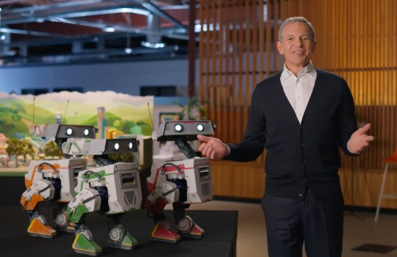Disney CEO Bob Iger stands alongside BDX droids OSKAR-7, BESH-27, and GREK-17 during the 2025 Disney Shareholder Meeting, highlighting the company’s innovation in robotics and their upcoming appearance in The Mandalorian and Grogu.