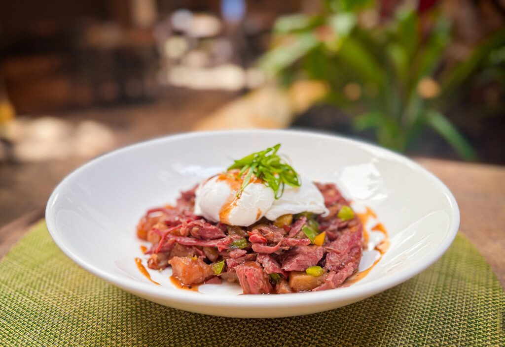 Corned Beef Hash at Tropicale – Poached eggs over corned beef, potatoes, and rosemary demi-glace.